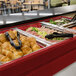 A red Cambro buffet bar base with trays of food on it.