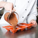 A chef pouring brown liquid into a Matfer Bourgeat silicone pyramid mold.