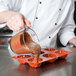A chef pouring liquid chocolate into a Matfer Bourgeat mini Kugelhopf mold.