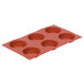 A red silicone fluted tart mold with six compartments.