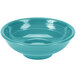A turquoise Fiesta china pedestal serving bowl with ripples on a blue surface.
