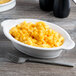 A white Fiesta oval casserole dish filled with macaroni and cheese on a table.
