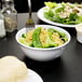 A bowl of noodles and broccoli in a white Thunder Group Nustone melamine bowl.
