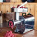 A Weston Pro Series electric meat grinder with meat in it on a wooden table.