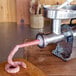 A sausage being pulled out of a Weston Pro Series Electric Meat Grinder.