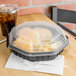 A Solo plastic take-out container with food and a drink in it, with a plastic fork on a napkin.
