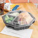 A Solo black plastic take-out container with a sandwich inside.