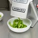 A Hobart food processor with a bowl of green peppers.