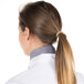 A woman with a ponytail wearing a houndstooth patterned Intedge chef neckerchief.