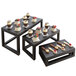 A table with American Metalcraft black wood risers holding small cupcakes.