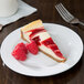 A slice of cheesecake with raspberries on a CAC Roosevelt porcelain plate.