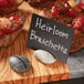A plate of bruschetta with a sign reading "heimbrusta" displayed on an American Metalcraft gray stone table card holder.