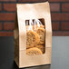 A Choice brown kraft paper bag with a clear window holding cookies on a table.