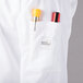 A white Mercer Culinary long sleeve chef jacket with a pocket full of tools.