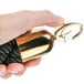 A hand holding a black braided rope with gold ends.