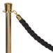 A black braided rope tied to a gold metal pole.