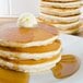 A stack of pancakes with butter and syrup.