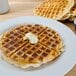 A plate with waffles and butter on top.