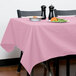 A table with a pink Intedge tablecloth and plates of food on it.