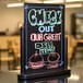 A black American Metalcraft table top board with colorful writing that says "Check out our great gift items"