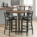 A Lancaster Table & Seating black cast iron bar height table base with chairs around it.