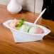 A white Fineline Flairware oval plastic bowl filled with three scoops of ice cream on a tray.