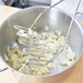 A person using a Thunder Group Chrome Plated Square-Faced Potato Masher to mash potatoes in a pot.