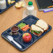 A Carlisle blue 6 compartment tray with a sandwich, apple, and a drink.