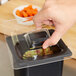 A hand using a Carlisle Clear Food Pan Lid on a plastic container on a counter.