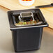 A clear Carlisle food pan lid on a black container on a counter.