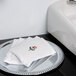 A silver tray with a stack of white Hoffmaster Linen-Like Floral Mist guest towels with a rose on top.