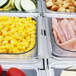 A Turbo Air refrigerated buffet table with trays of food including corn and sliced ham.
