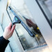 A hand holding a Unger ErgoTec window squeegee to a window.