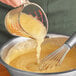 A person using a whisk to stir Regal sweetened applesauce in a bowl.