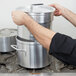 A person using a Vollrath aluminum double boiler set on a stove.