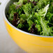 A Vollrath double wall metal serving bowl filled with green leafy vegetables.