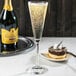 A Libbey trumpet flute filled with champagne on a table next to a dessert plate.