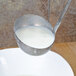 A Vollrath stainless steel ladle pouring white liquid into a bowl.