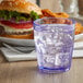 A blue Bahama plastic tumbler filled with ice water on a table with a hamburger.