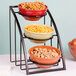 A Cal-Mil black round bowl display stand holding three bowls of food.