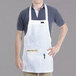 A man wearing a white Chef Revival bib apron with a pocket.