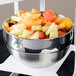 A Vollrath metal bowl filled with fruit on a table.