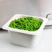 A Cambro white polycarbonate food pan filled with green peas.