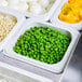 A white Cambro food pan with a tray of food including peas, carrots, and other vegetables.