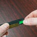 A person holding a small rectangular black and green Unger squeegee blade.