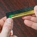 A person's hand holding a green and black Unger ErgoTec squeegee blade.