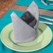 A folded Intedge gray cloth napkin on a plate.