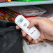 A hand using a Taylor digital infrared thermometer to check a refrigerator temperature.