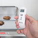 A person using a Taylor digital infrared thermometer to check cookies in a school kitchen.