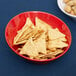 A red GET Red Sensation melamine bowl filled with crackers and nuts on a table.